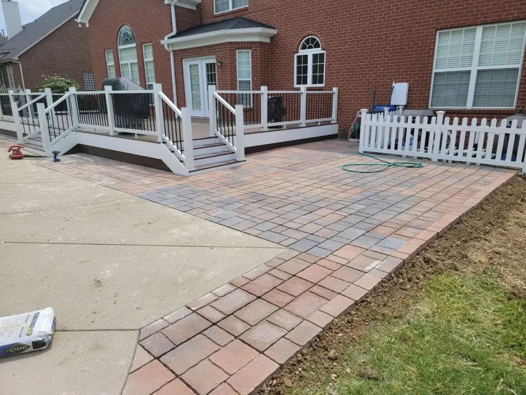 White-railed deck with steps down to a new paver patio