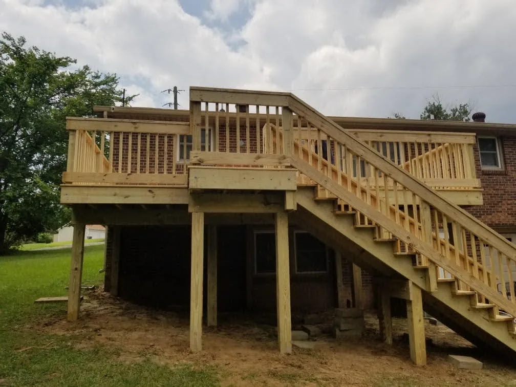 Elevated pressure-treated deck with long staircase to a sloped backyard