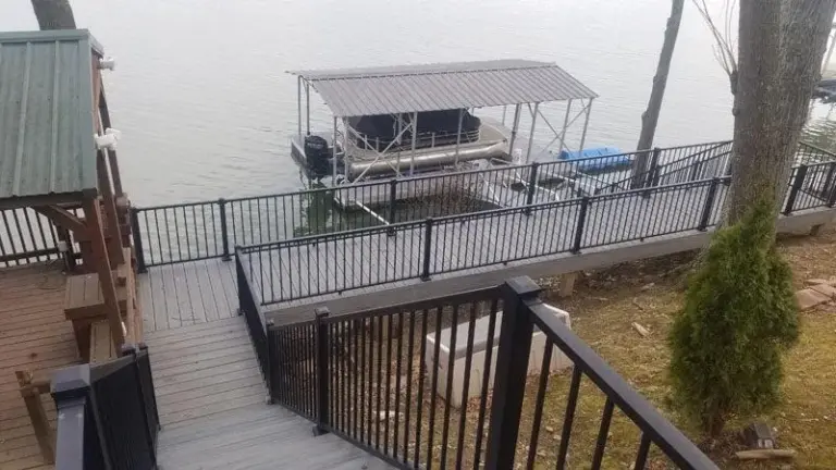 Lakeside composite deck with black aluminum railing overlooking a boat dock