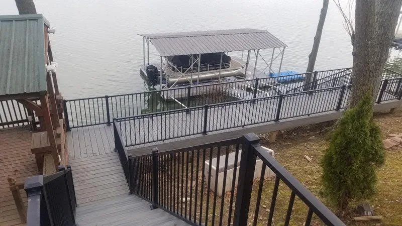 Lakeside composite deck with black aluminum railing overlooking a boat dock
