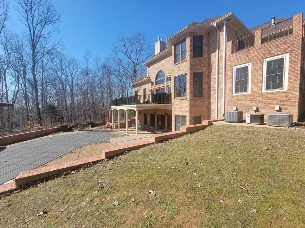 Multi-level deck and patio wrapping the rear of a large brick home
