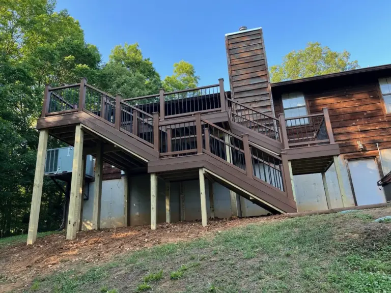 Multi-level stained deck with dark railing running along a hillside home